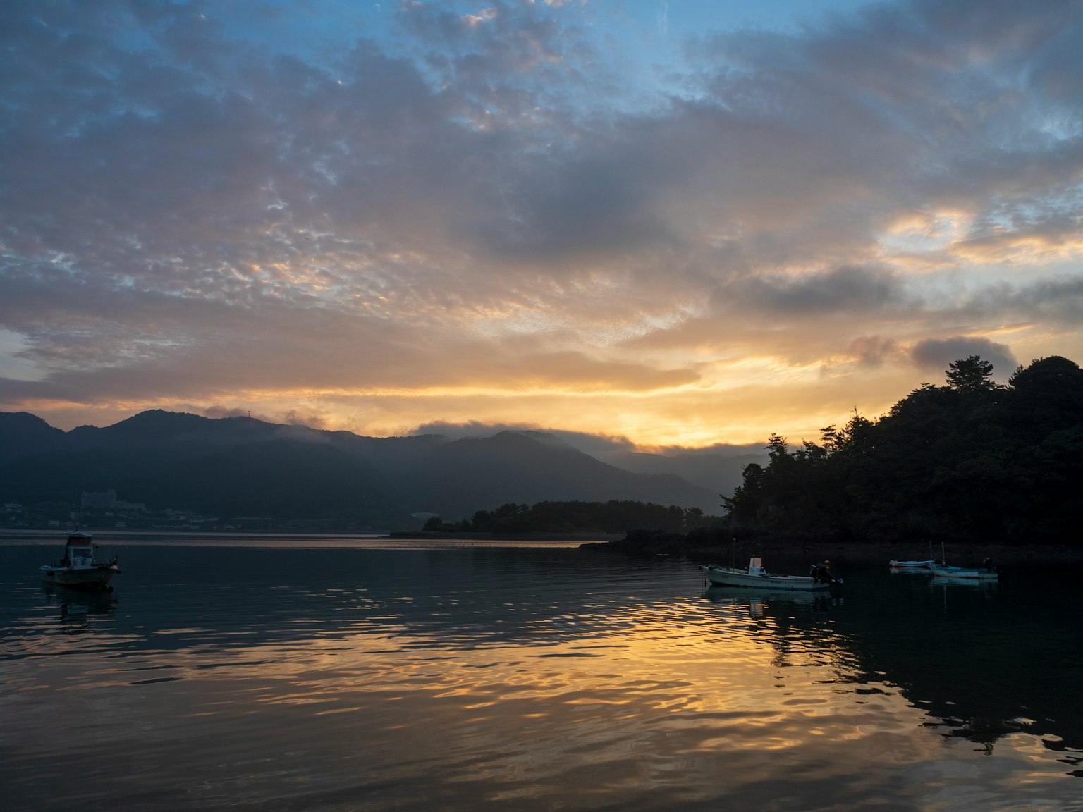 Pemandangan matahari terbenam yang indah tercermin di danau dengan perahu mengapung