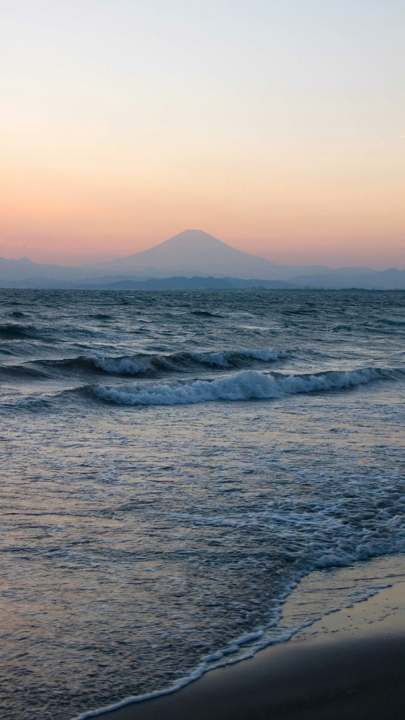 平静的海洋与日落背景的山