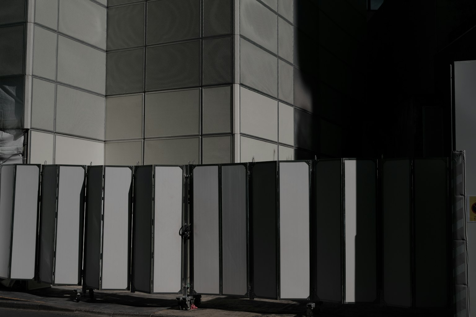 Structure with alternating white and gray panels against a building wall