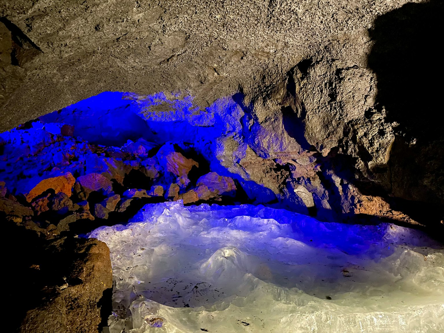Interno di una grotta con luce blu che illumina la superficie dell'acqua e le rocce