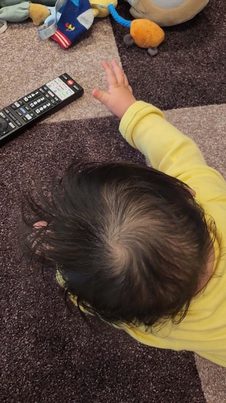 一个穿着黄色衬衫的婴儿正在伸手去拿玩具