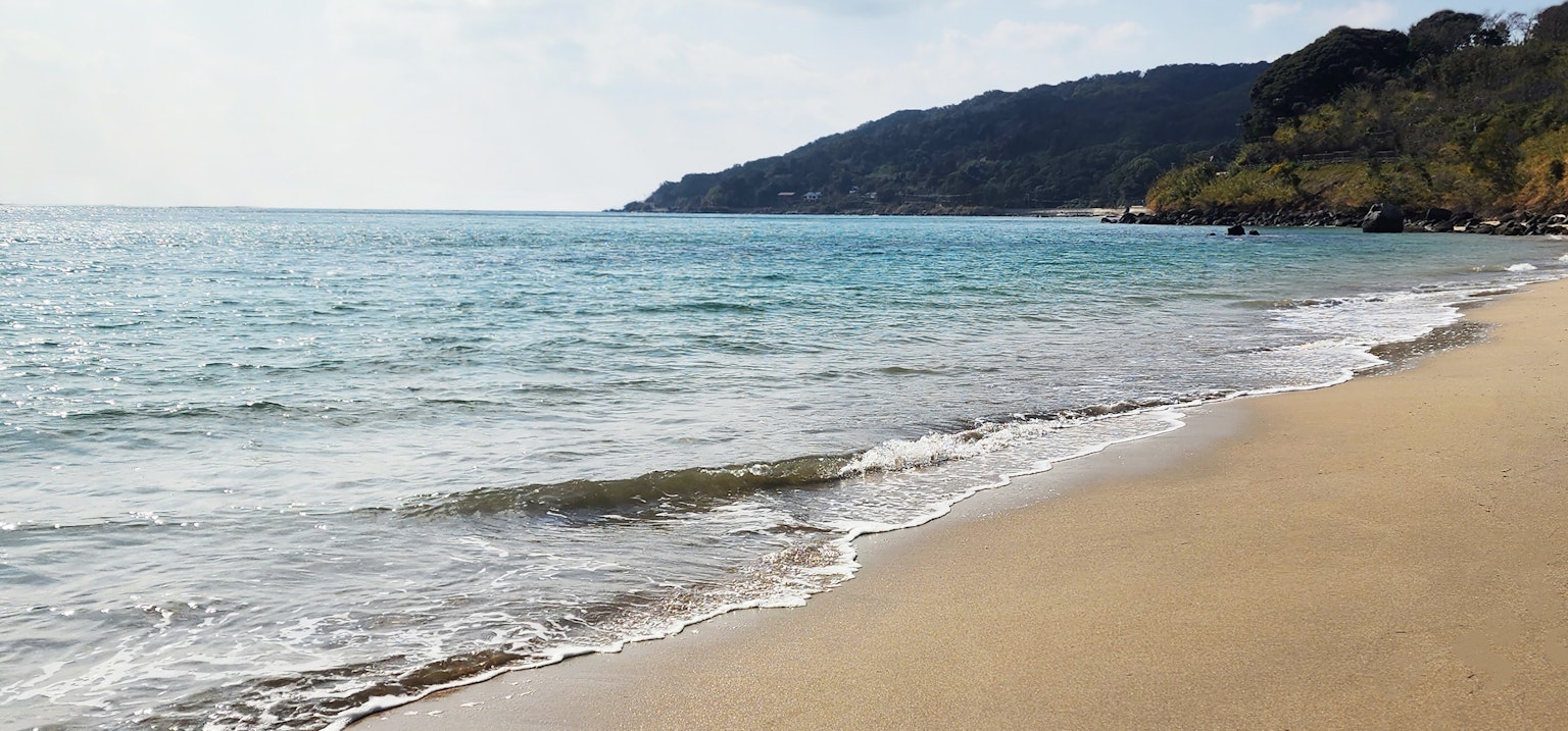 Scène de plage sereine avec des vagues douces mer bleue et rivage sableux avec des collines en arrière-plan