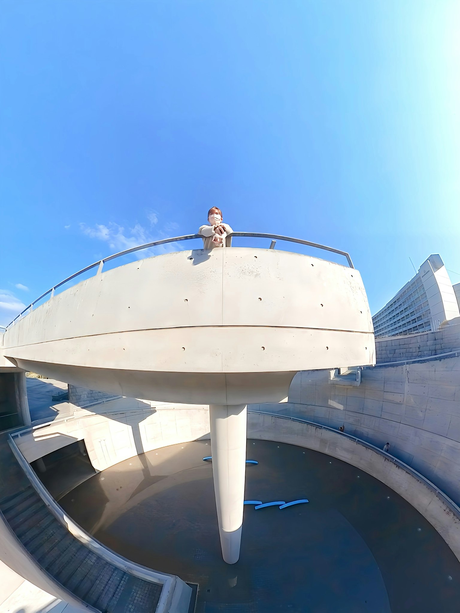 A person sitting on a concrete structure under the blue sky
