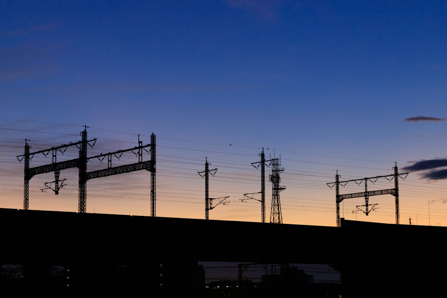 Silhouette of railway overhead lines against a sunset sky