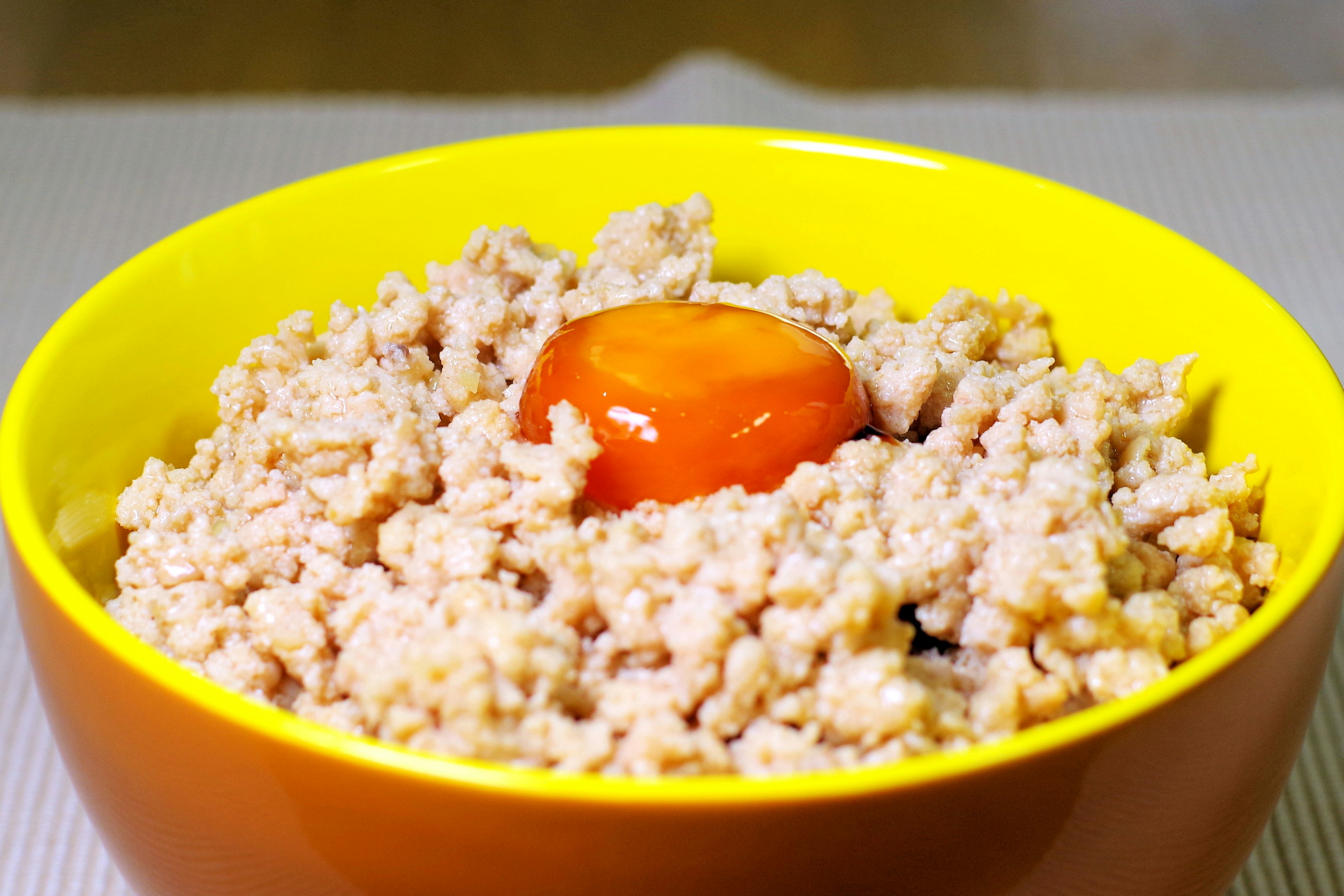黃色碗裡鋪著橘色蛋黃般的配料與碎狀食材