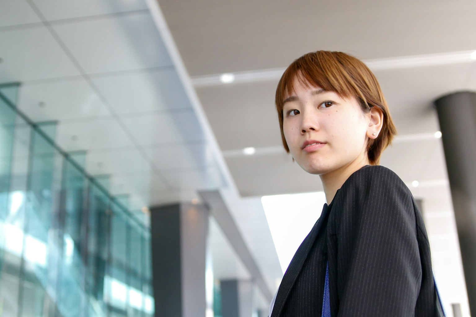 비즈니스 정장을 입은 여성이 현대적인 건물 앞에 서 있다