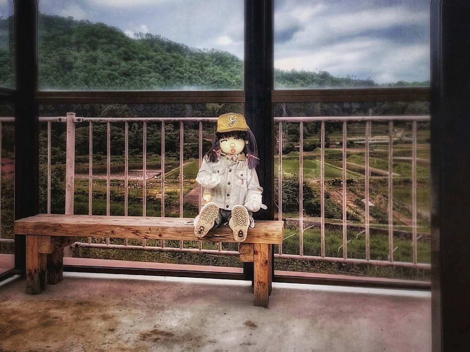 모자를 쓴 작은 인형이 나무 벤치에 앉아 있는 경치