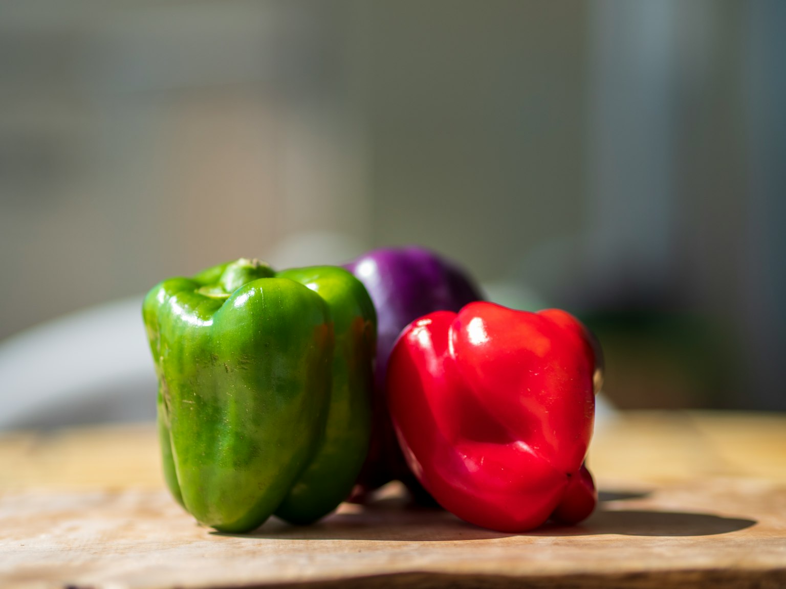 Poivrons verts rouges et violets disposés sur une planche en bois