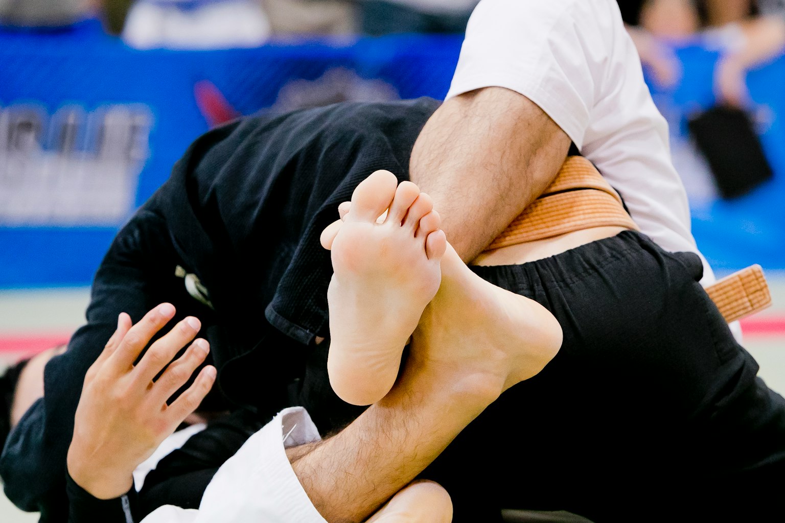 Two judo fighters entangled in a grappling position with feet intertwined