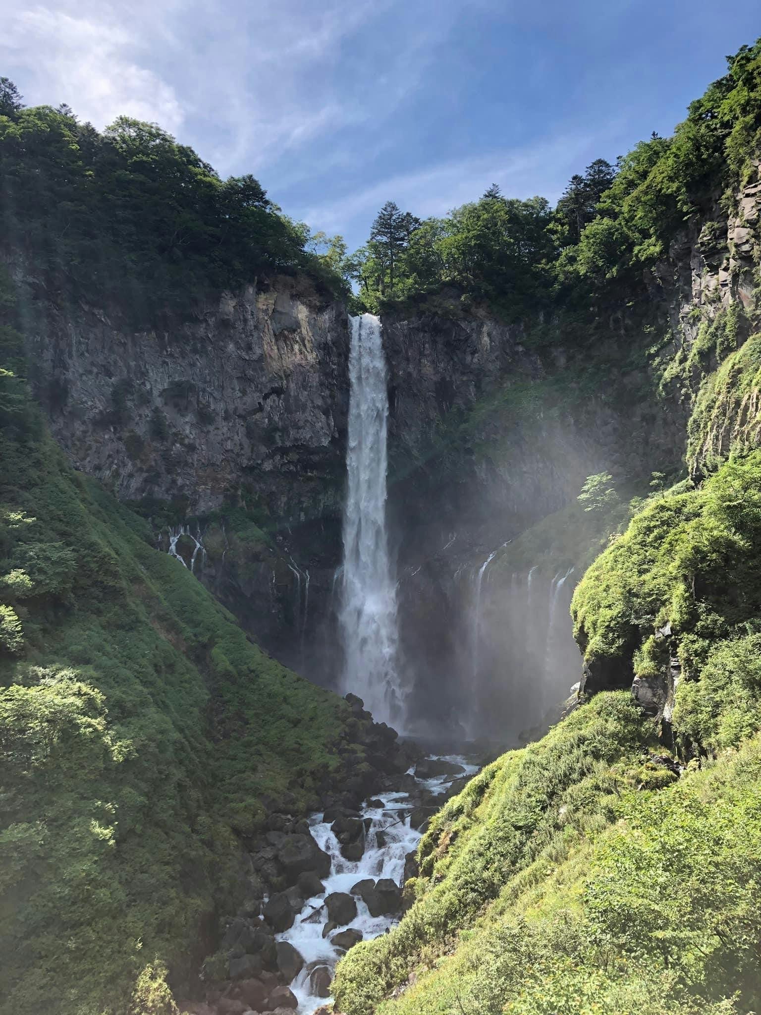 Une belle cascade tombant entourée de montagnes verdoyantes