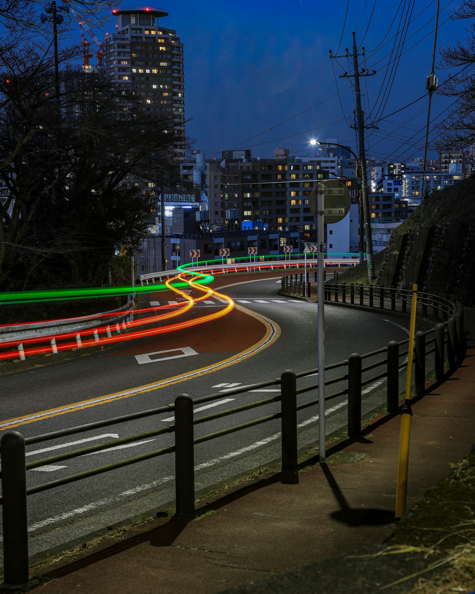 弯曲的道路与车辆光轨在夜间城市景观下