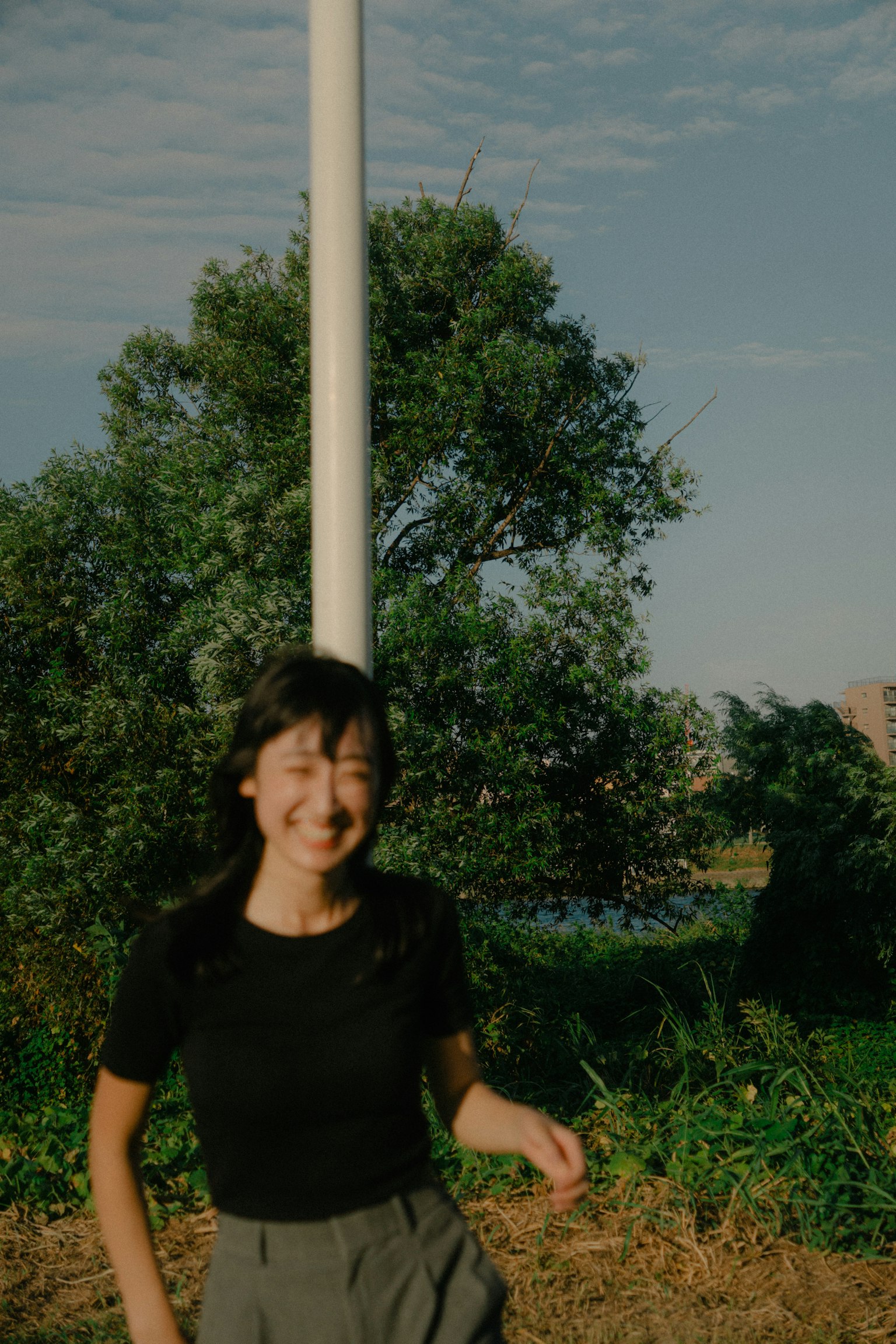 Eine lächelnde Frau, die in einer grünen Umgebung mit Bäumen und blauem Himmel läuft