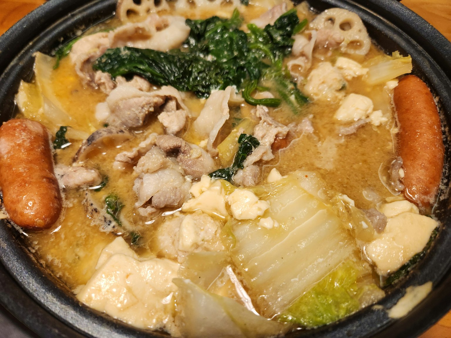 Hidangan hot pot lezat dengan daging babi, tahu, dan sayuran campuran