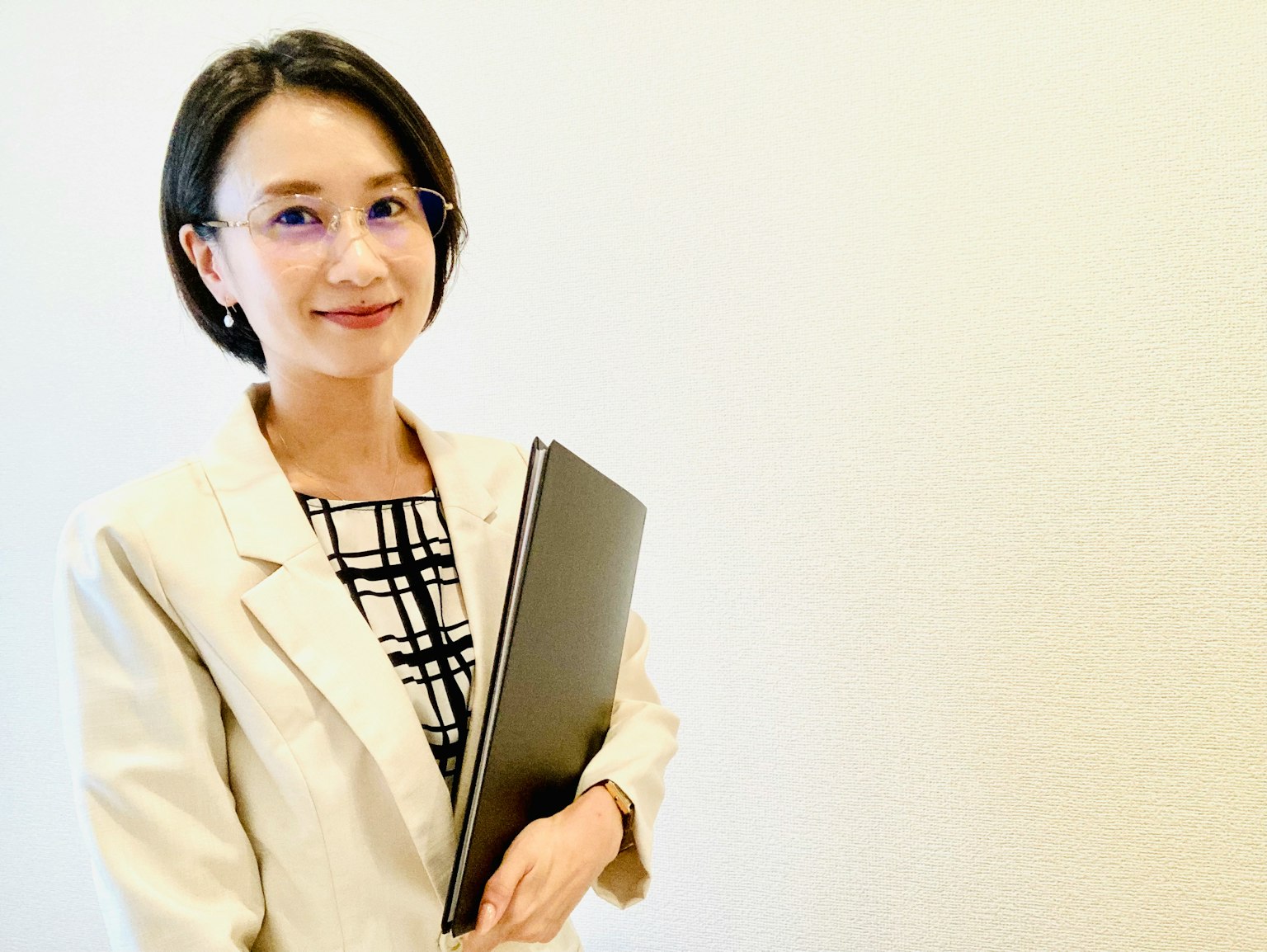 一位穿著商務套裝的女性手持筆記型電腦