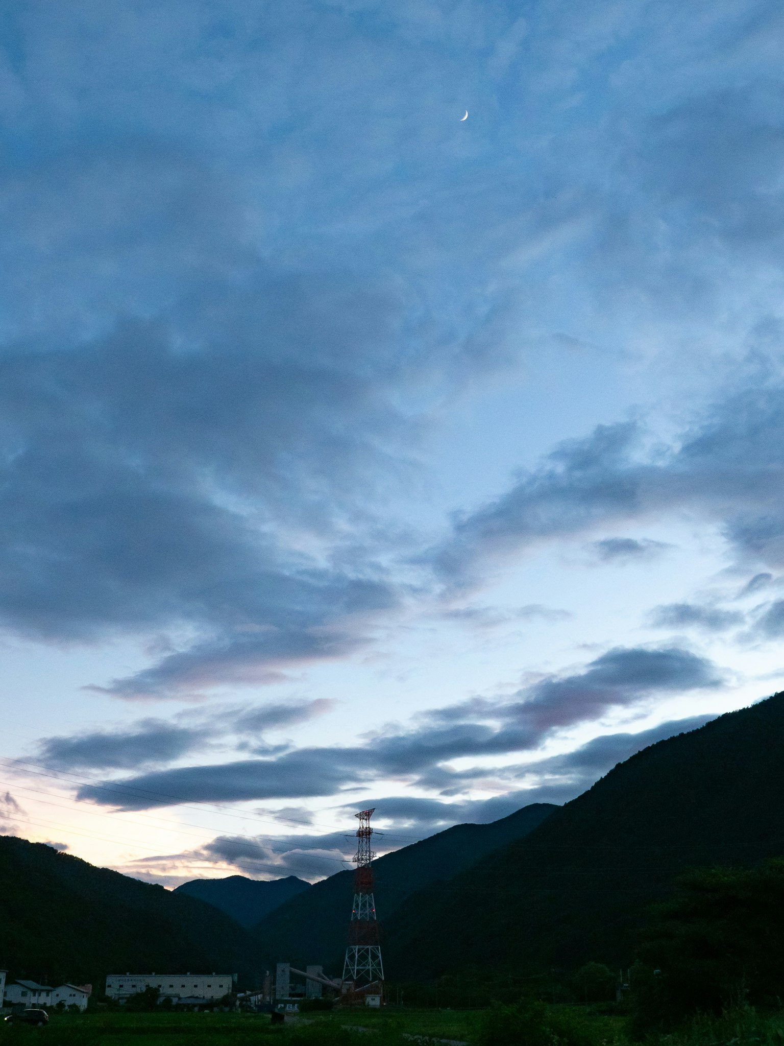 Paesaggio montano con cielo blu e nuvole che presenta una piccola torre