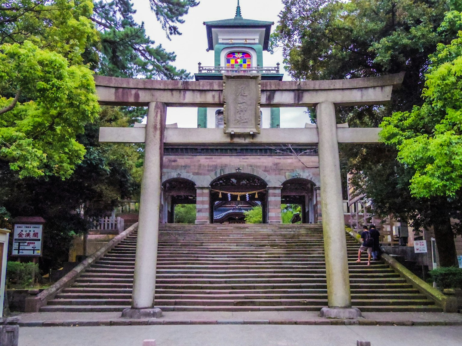 神社的主入口，有鸟居和台阶，周围被郁郁葱葱的绿树环绕