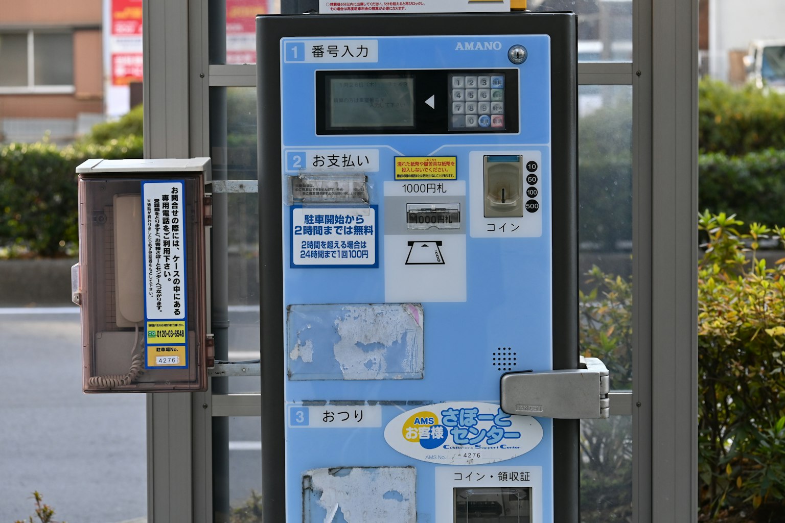 Distributeur automatique bleu situé dans une zone verte avec de la végétation environnante