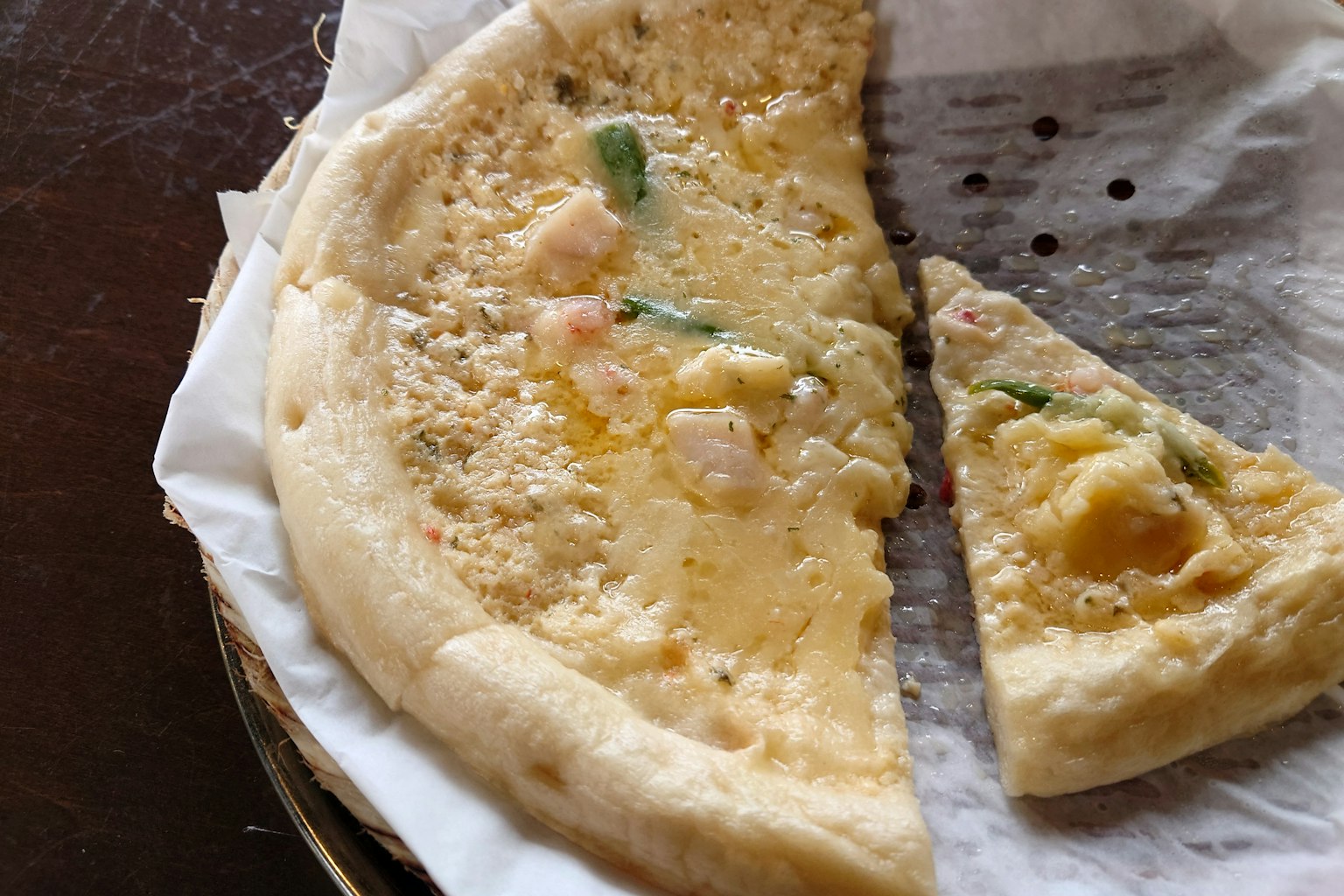 Dünner Pizzaboden mit Belag und einem geschnittenen Stück