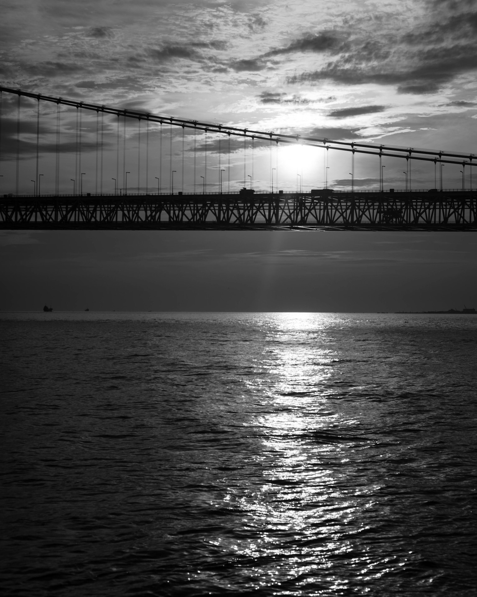 Paesaggio in bianco e nero con un ponte e riflesso del tramonto sull'acqua