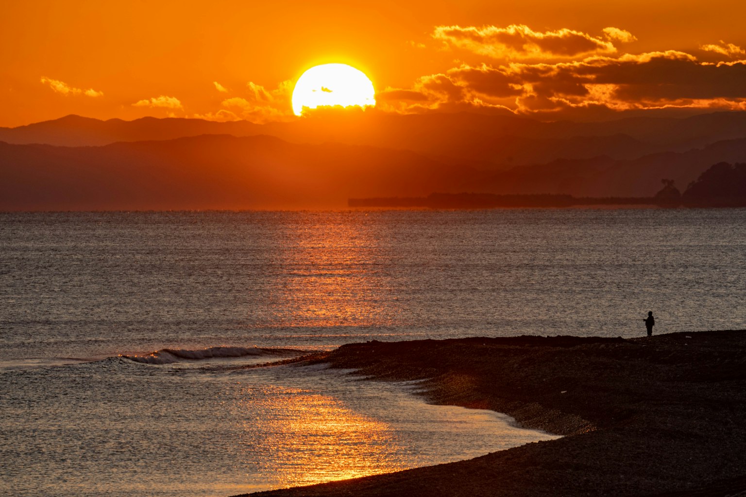 Schöne Landschaft des Sonnenuntergangs über dem Meer mit einer Silhouette am Strand