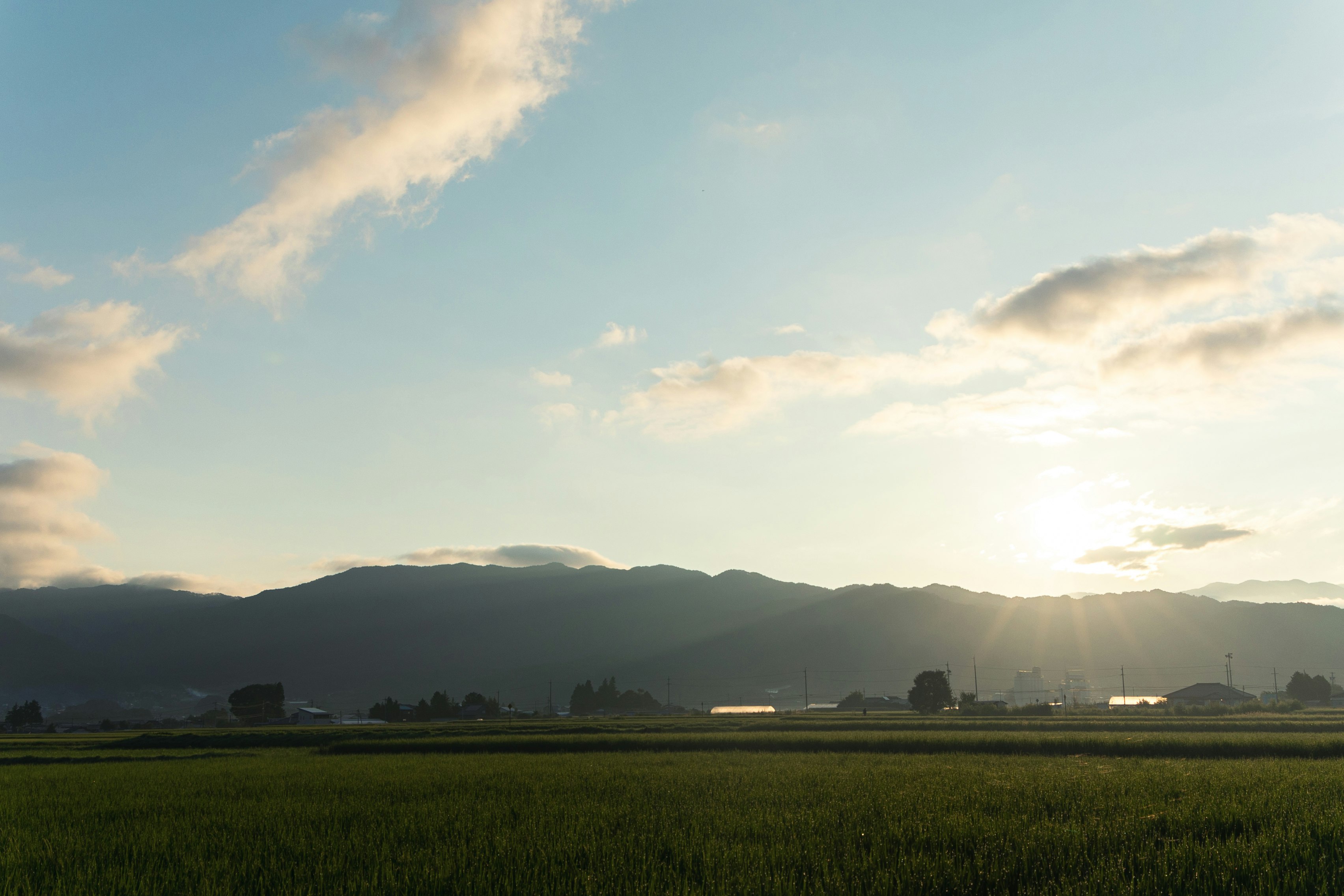 coucher de soleil sur un paysage rural et des montagnes au loin