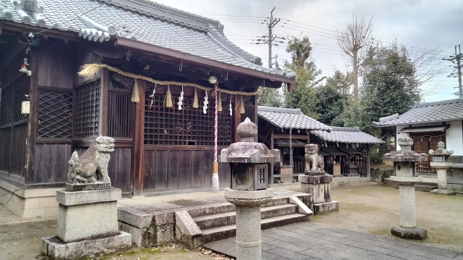 Traditional Japanese shrine scene featuring a wooden building and stone lanterns