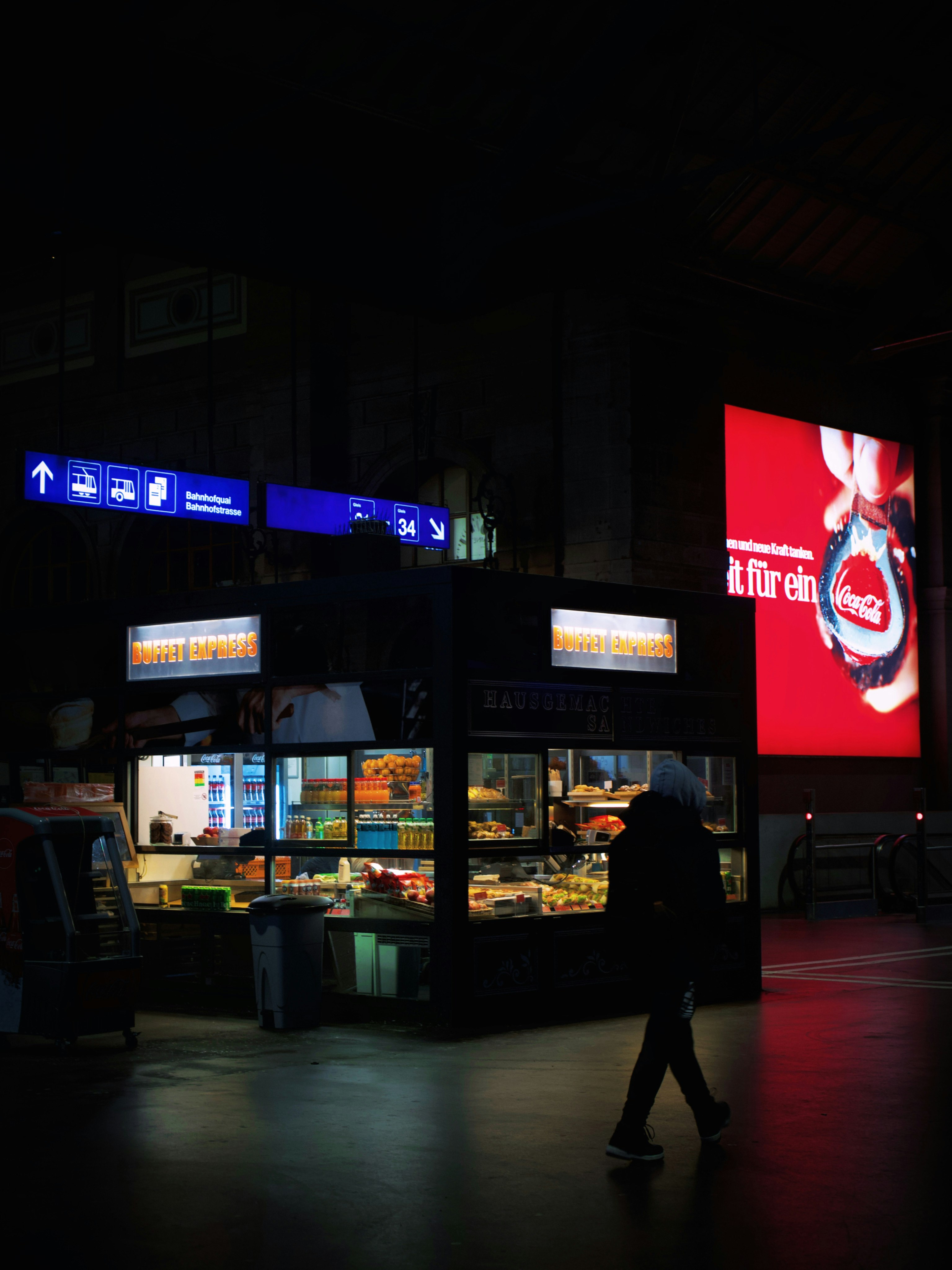 暗い駅の中での人影と明るい広告がある風景