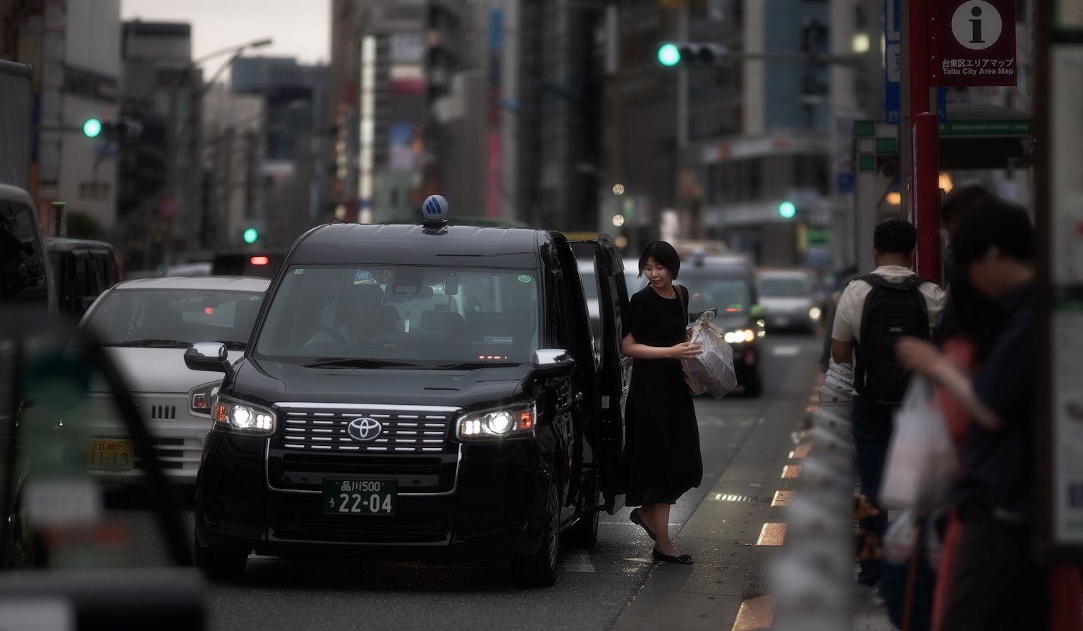 Seorang wanita keluar dari taksi di jalan Tokyo dengan lalu lintas