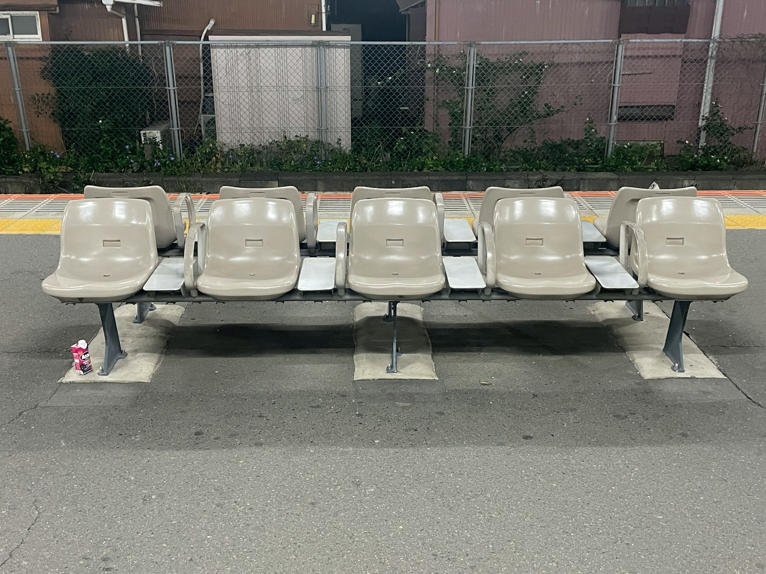 Reihe von beigen Sitzplätzen an einem Bahnhof bei Nacht