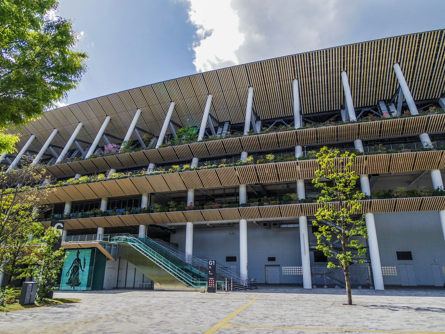Modern stadium exterior with balcony plants bright blue sky