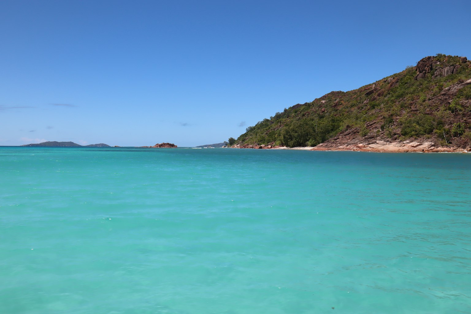 Escena de playa con agua turquesa y colinas verdes