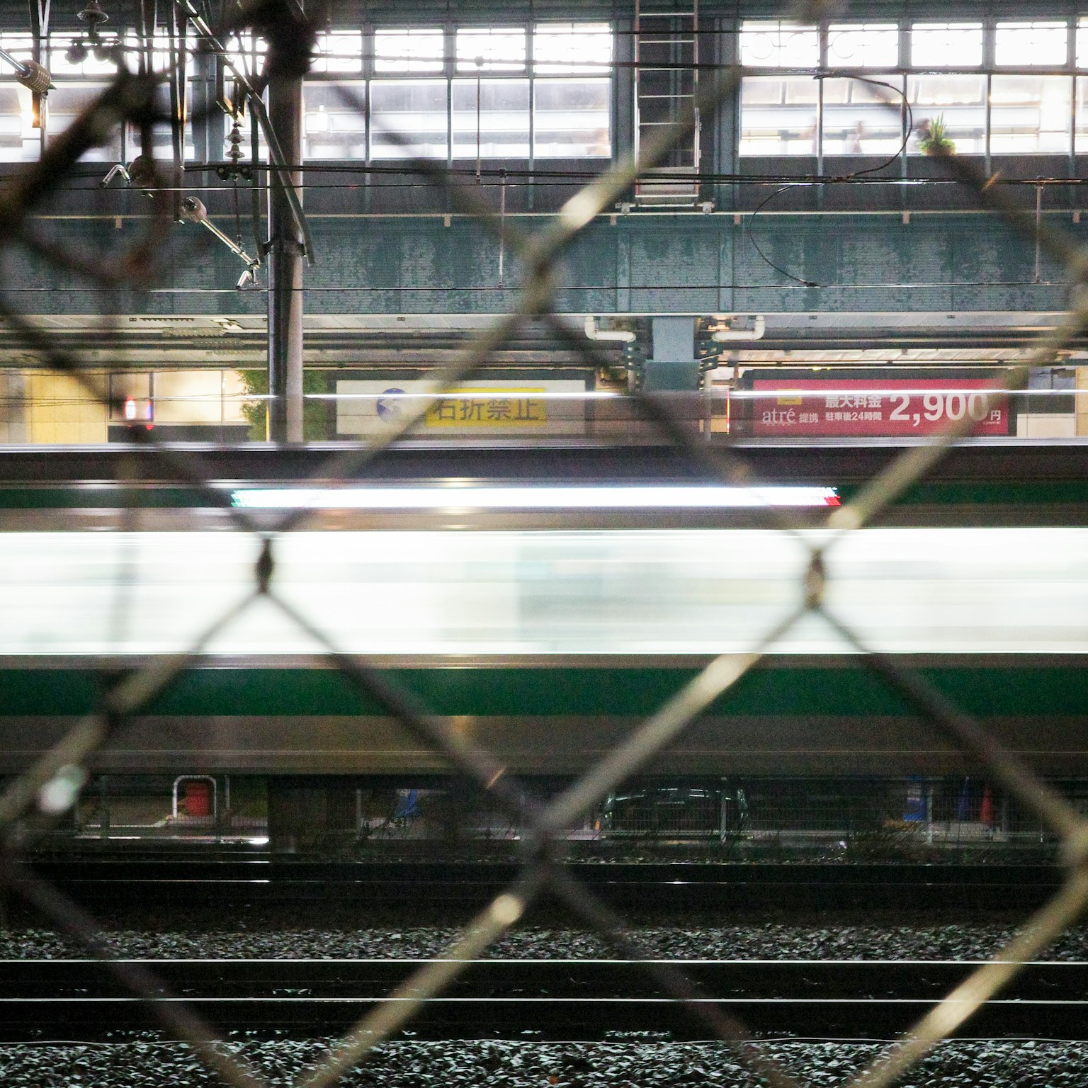 Kereta bergerak di stasiun kereta dengan pagar di latar depan