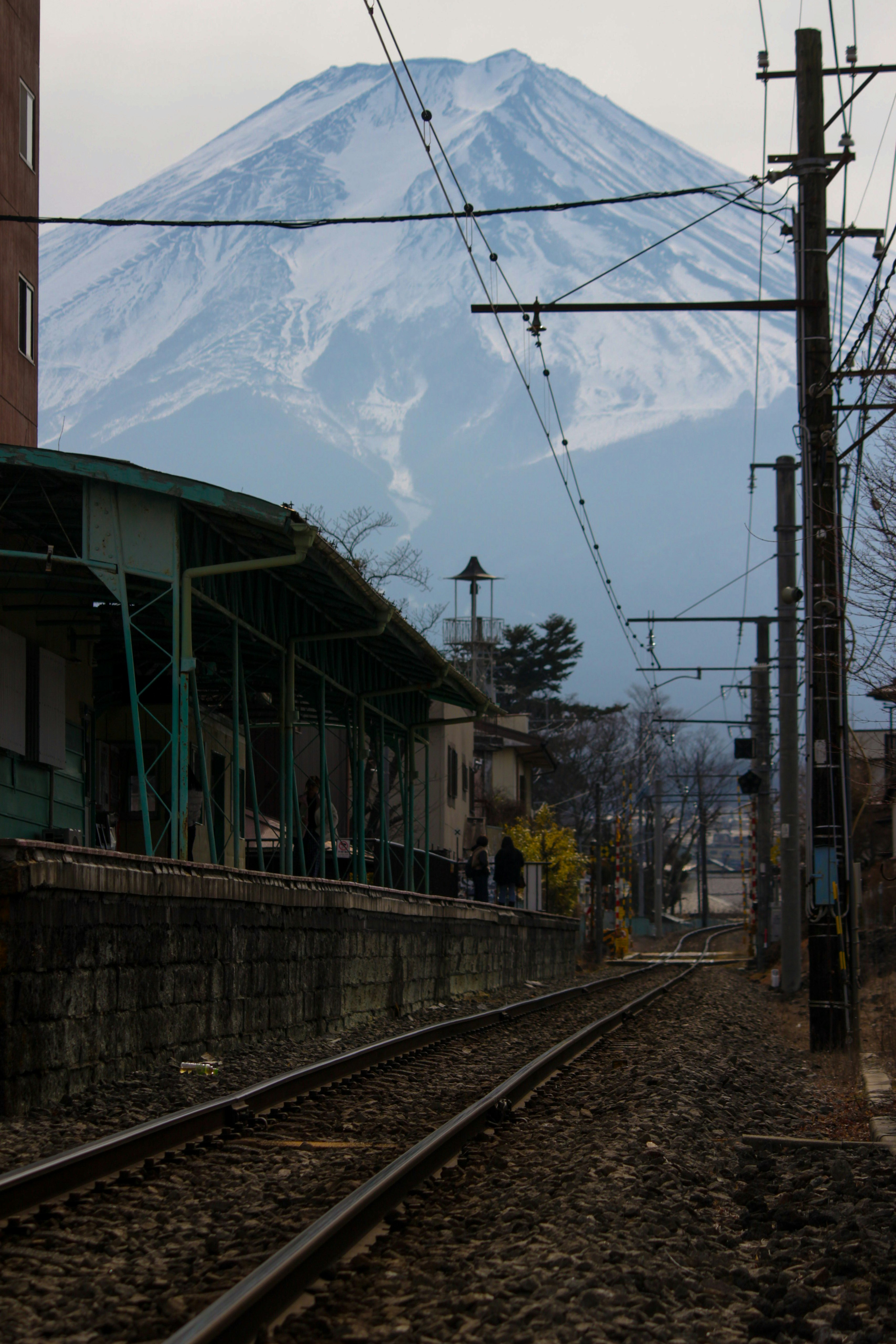 踏切から霞む富士山を望む線路と電柱の風景