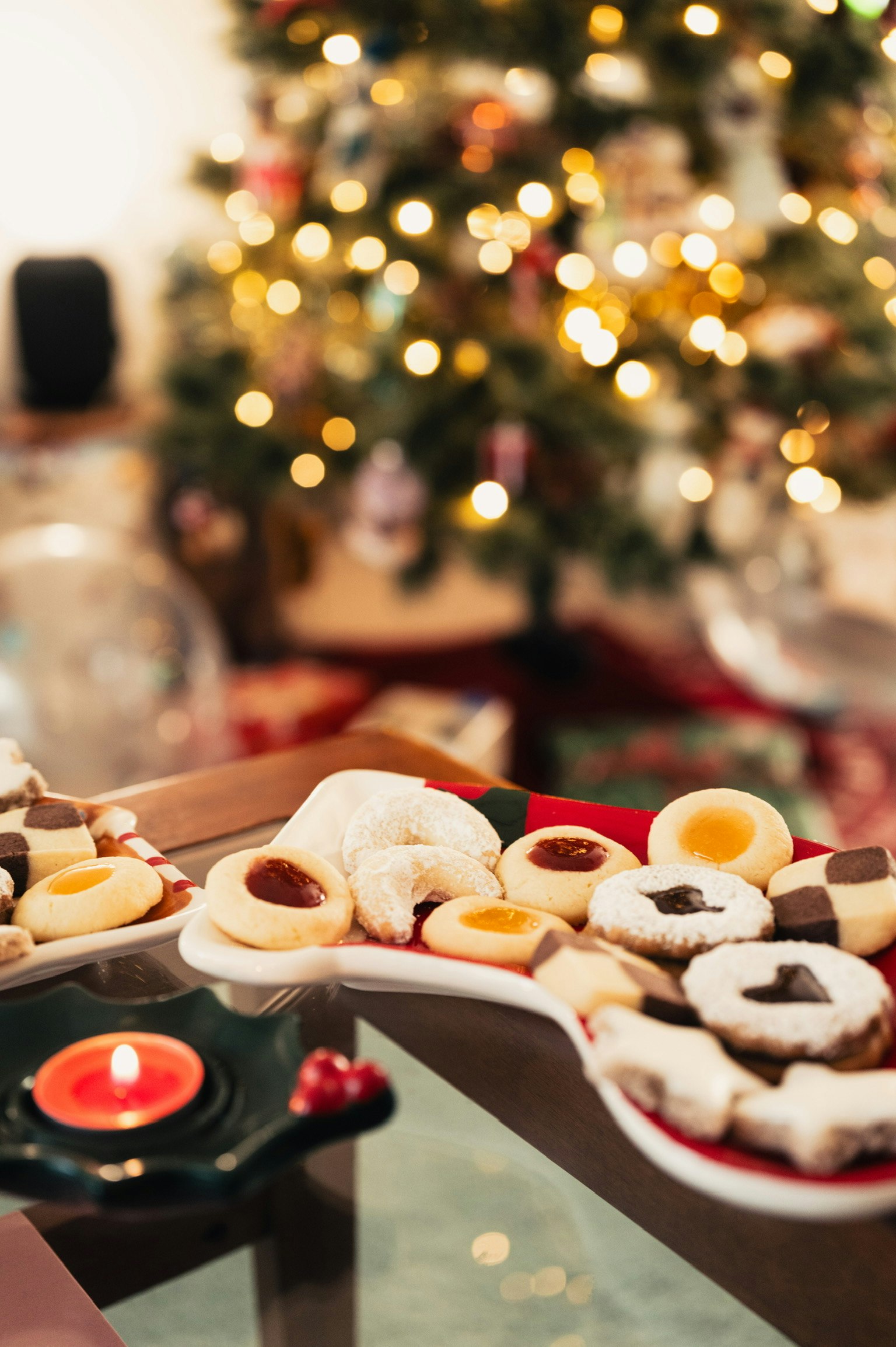 クリスマスツリーの前に置かれた色とりどりのクッキーとキャンドル