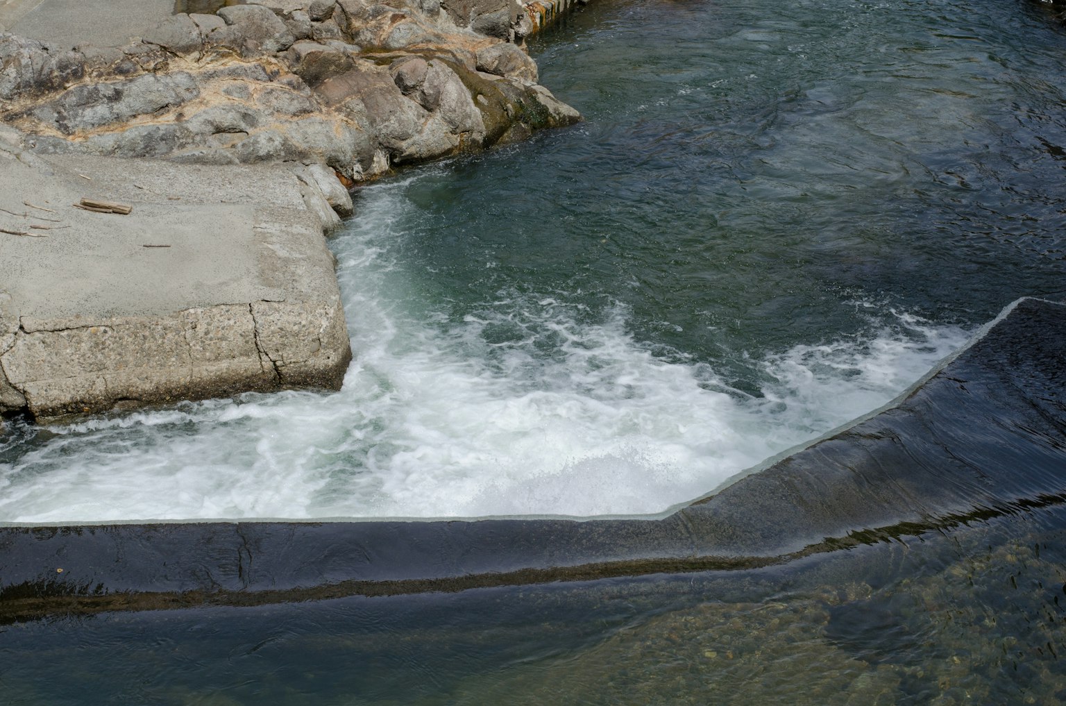 Fließendes Wasser über Felsen mit einer Betonkante