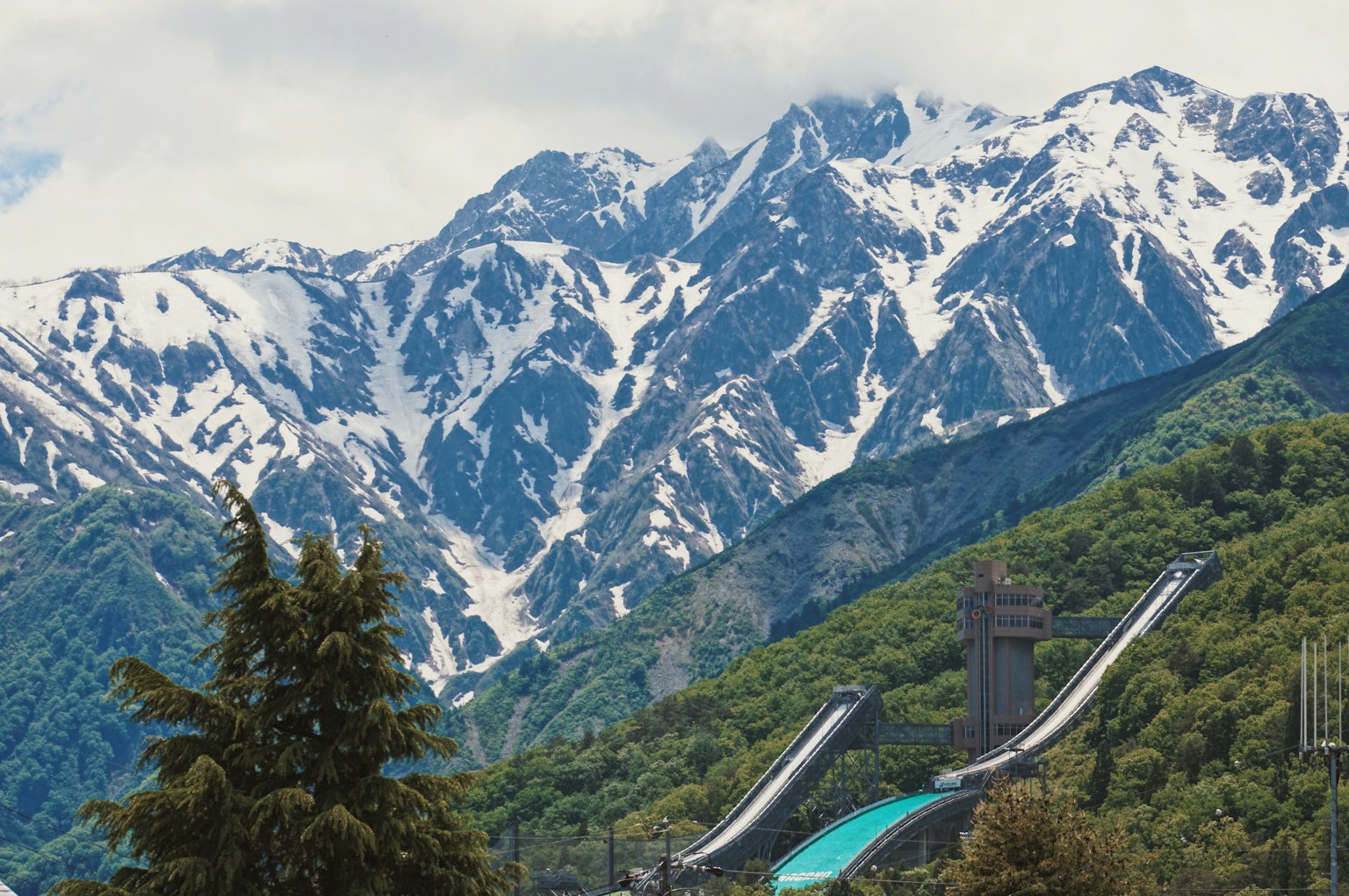 Montagnes enneigées avec une verdure luxuriante et des pistes de ski visibles