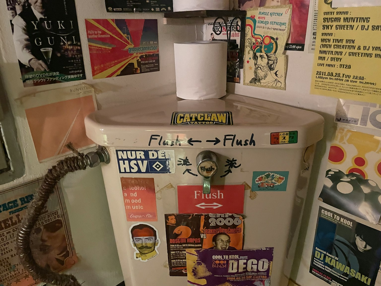 Toilet flush unit covered in various stickers and posters