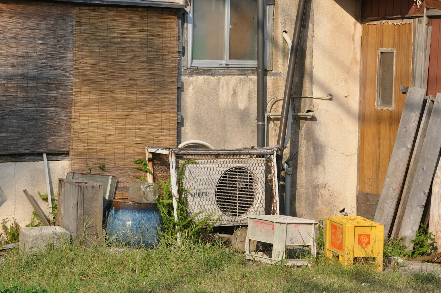 Una escena con una unidad de aire acondicionado y varios objetos detrás de una casa vieja