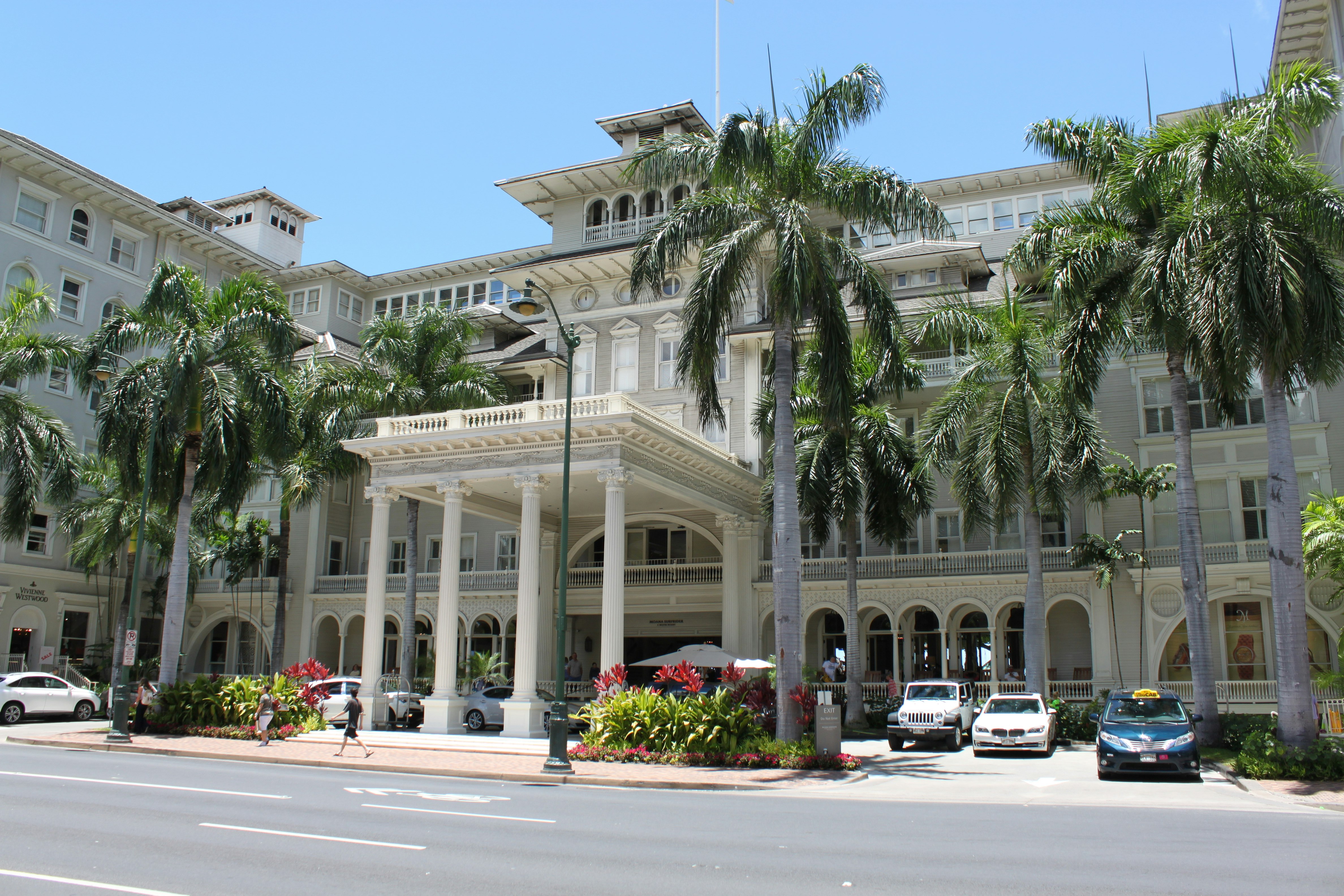 front of a large white building with palm-lined street