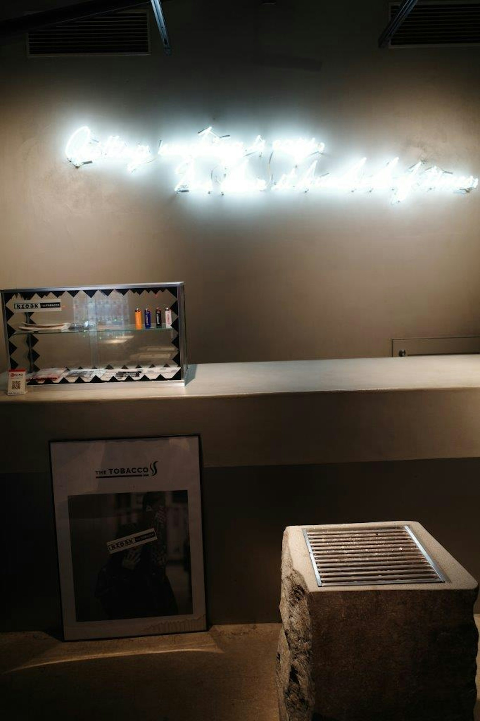 Spazio espositivo moderno con opere d'arte e testo illuminato