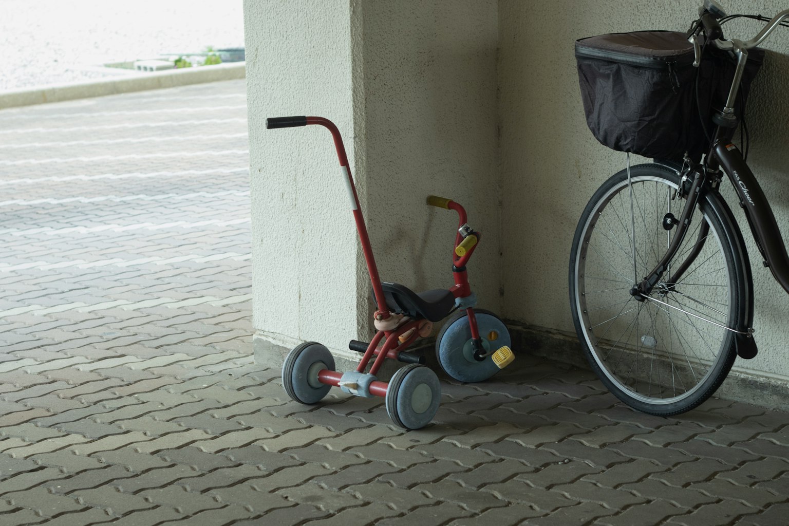 Triciclo rosso e bicicletta parcheggiati vicino a un muro