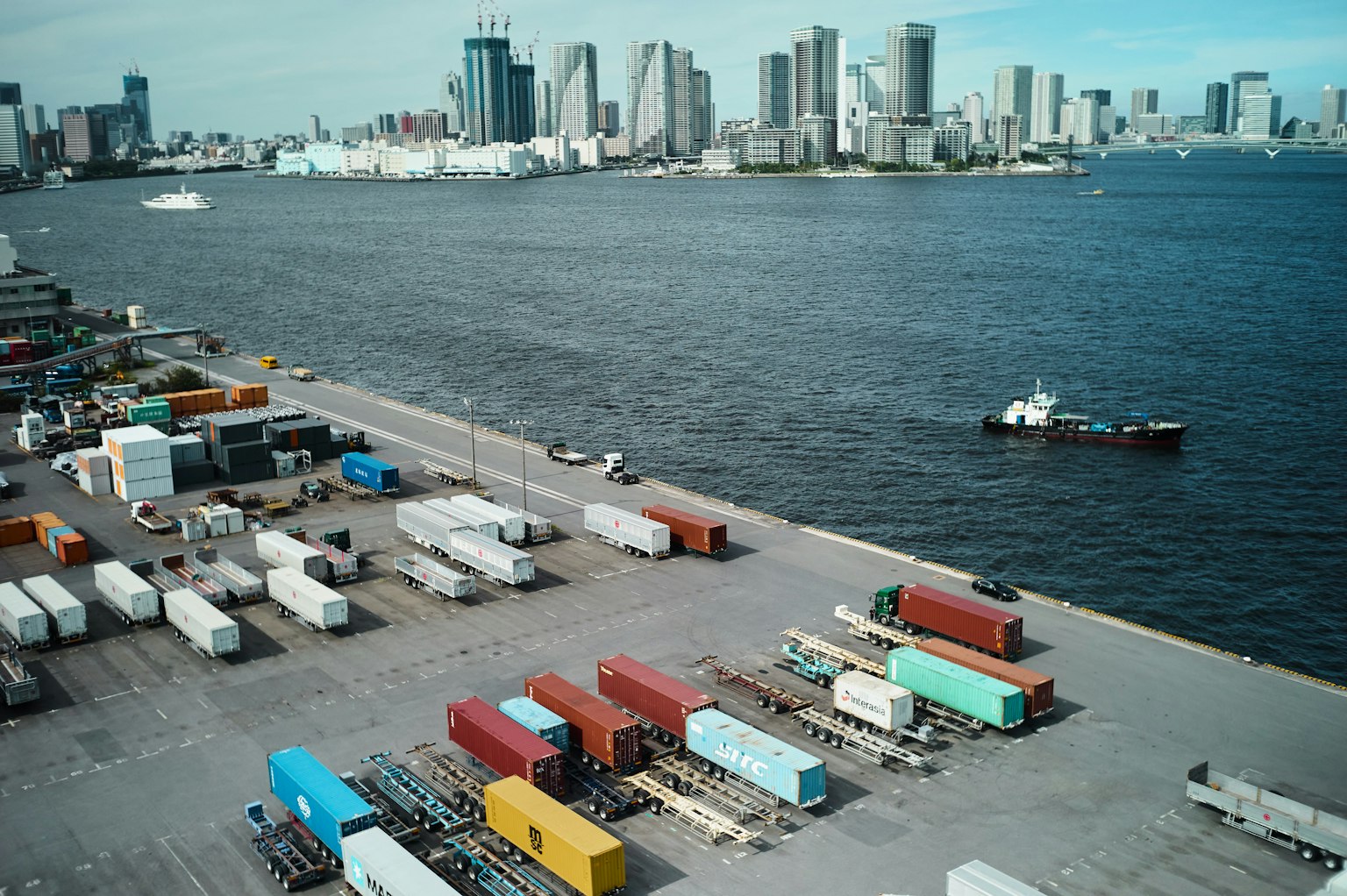 Vista aerea di container nel porto con lo skyline della città sullo sfondo