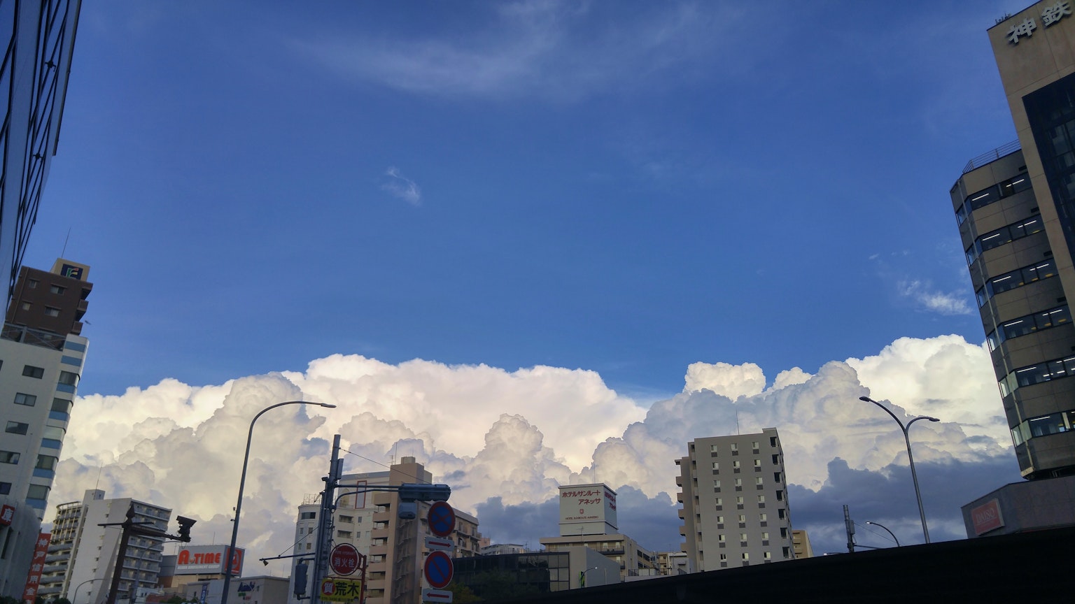 ทิวทัศน์เมืองที่มีท้องฟ้าสีฟ้าและเมฆขาวฟูฟ่อง