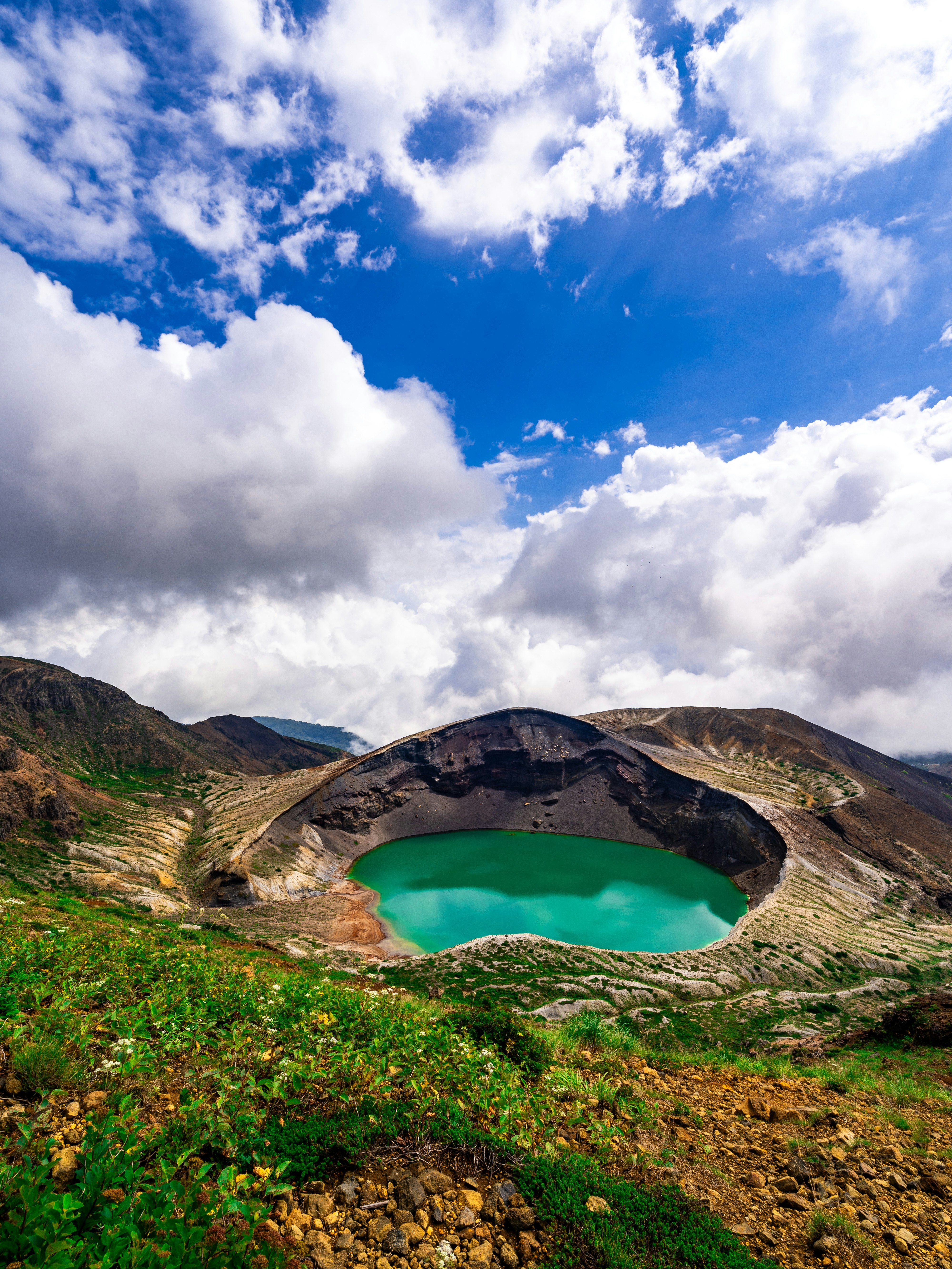 緑の湖がある山間の火口地形の風景
