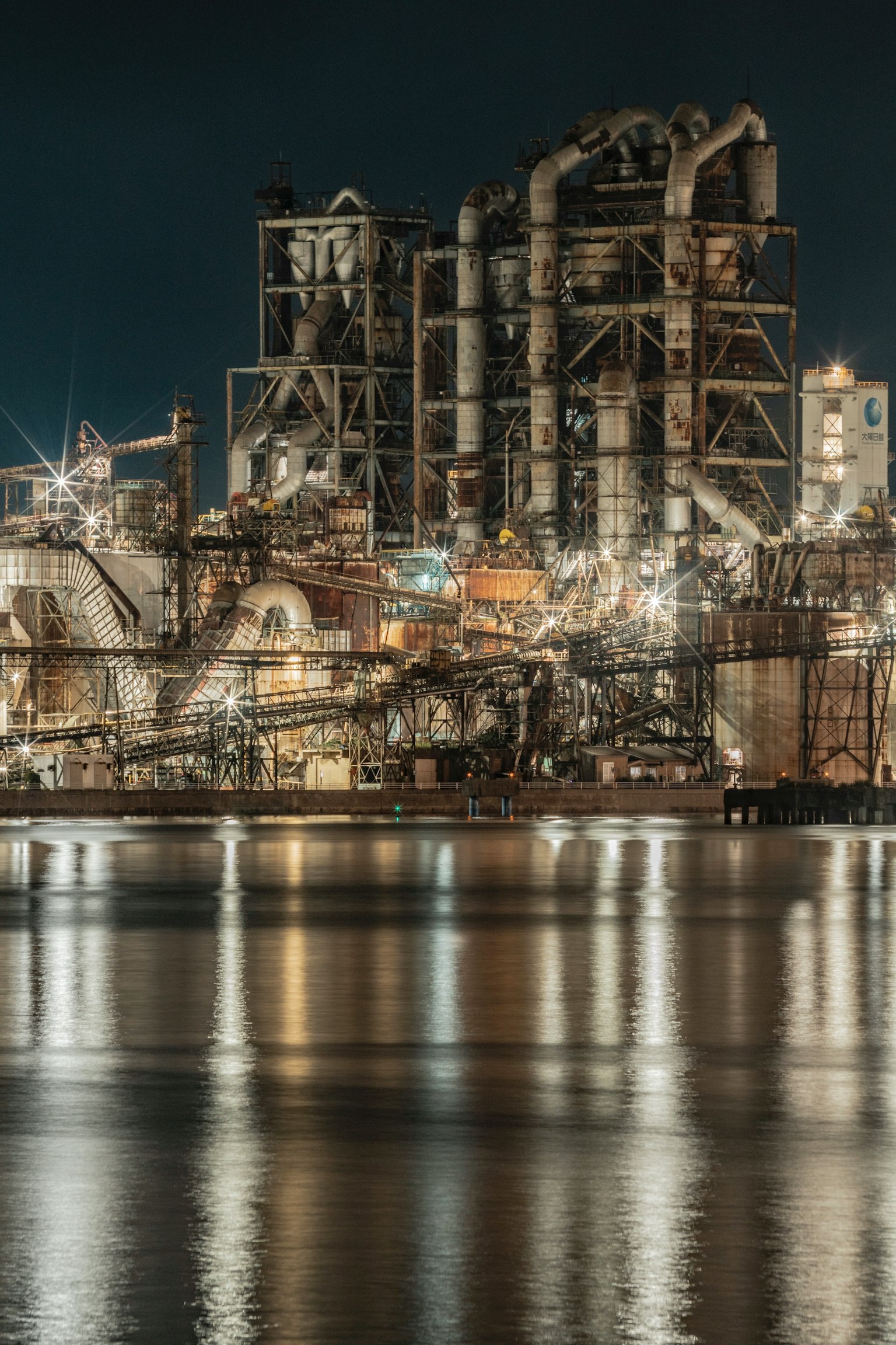 夜の工業地帯の景観 水面に映る工場の構造物と明かり