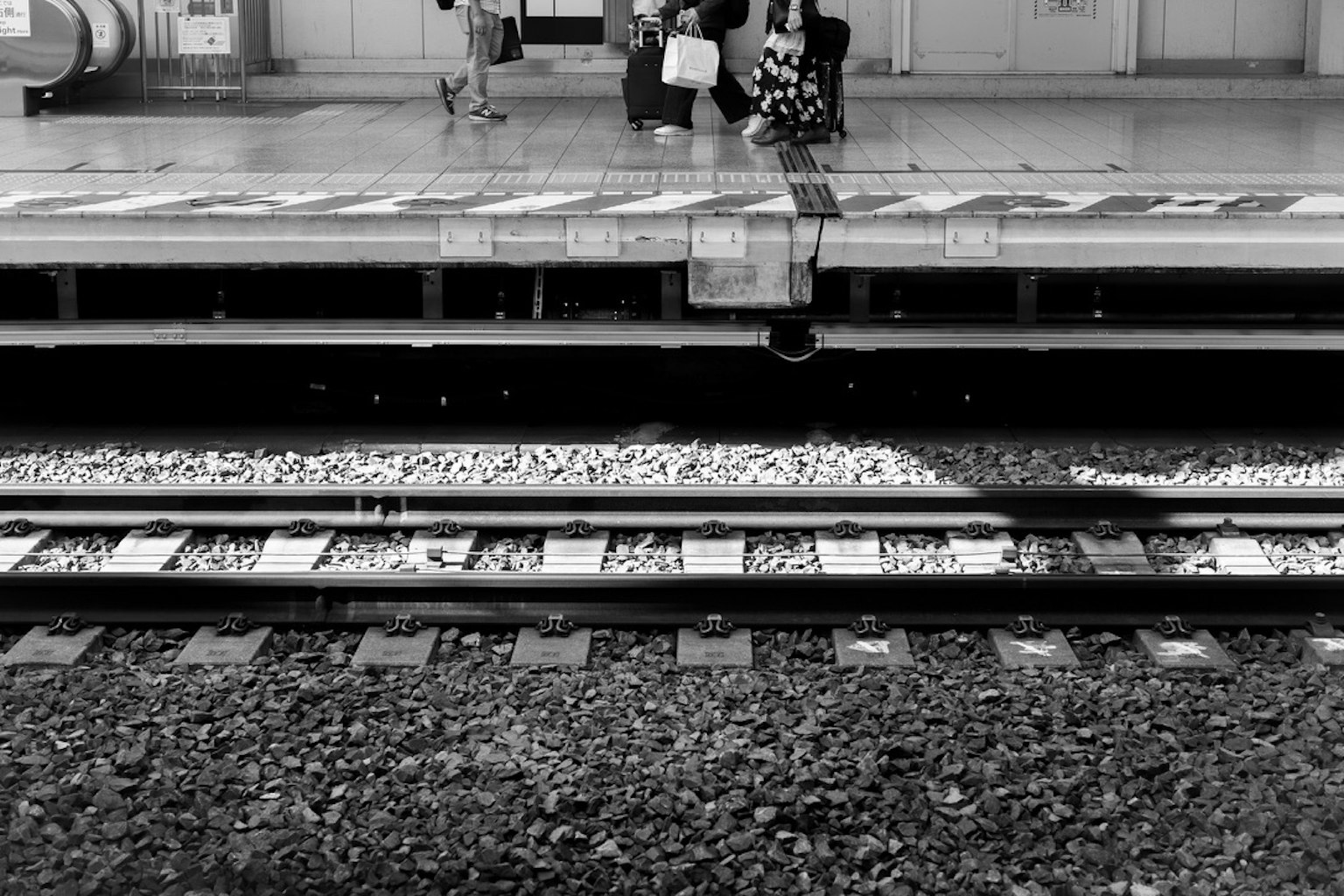 Black and white image of a train station platform and railway tracks