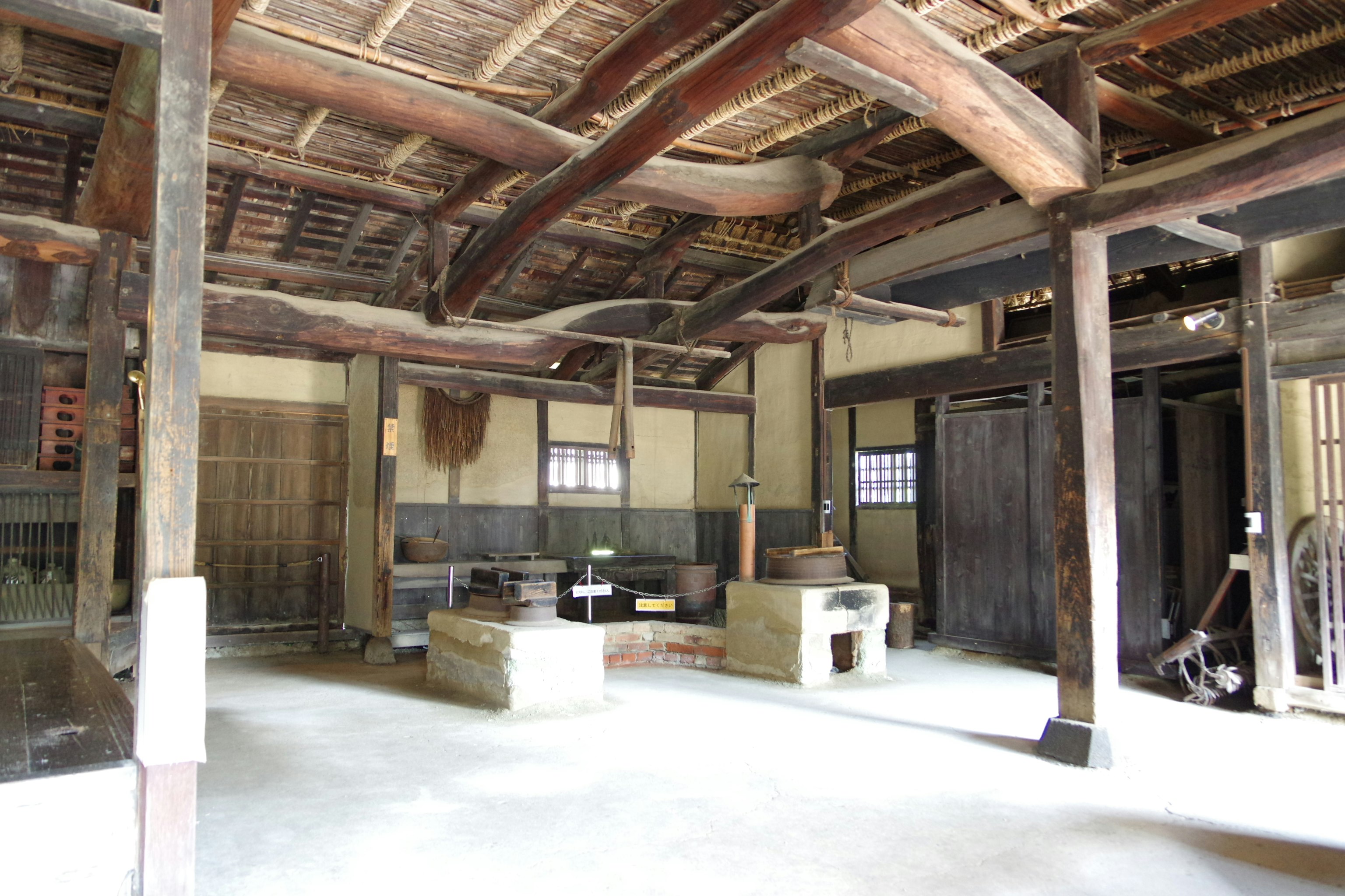 木造の古い建物内に並ぶ囲炉裏と梁のある空間
