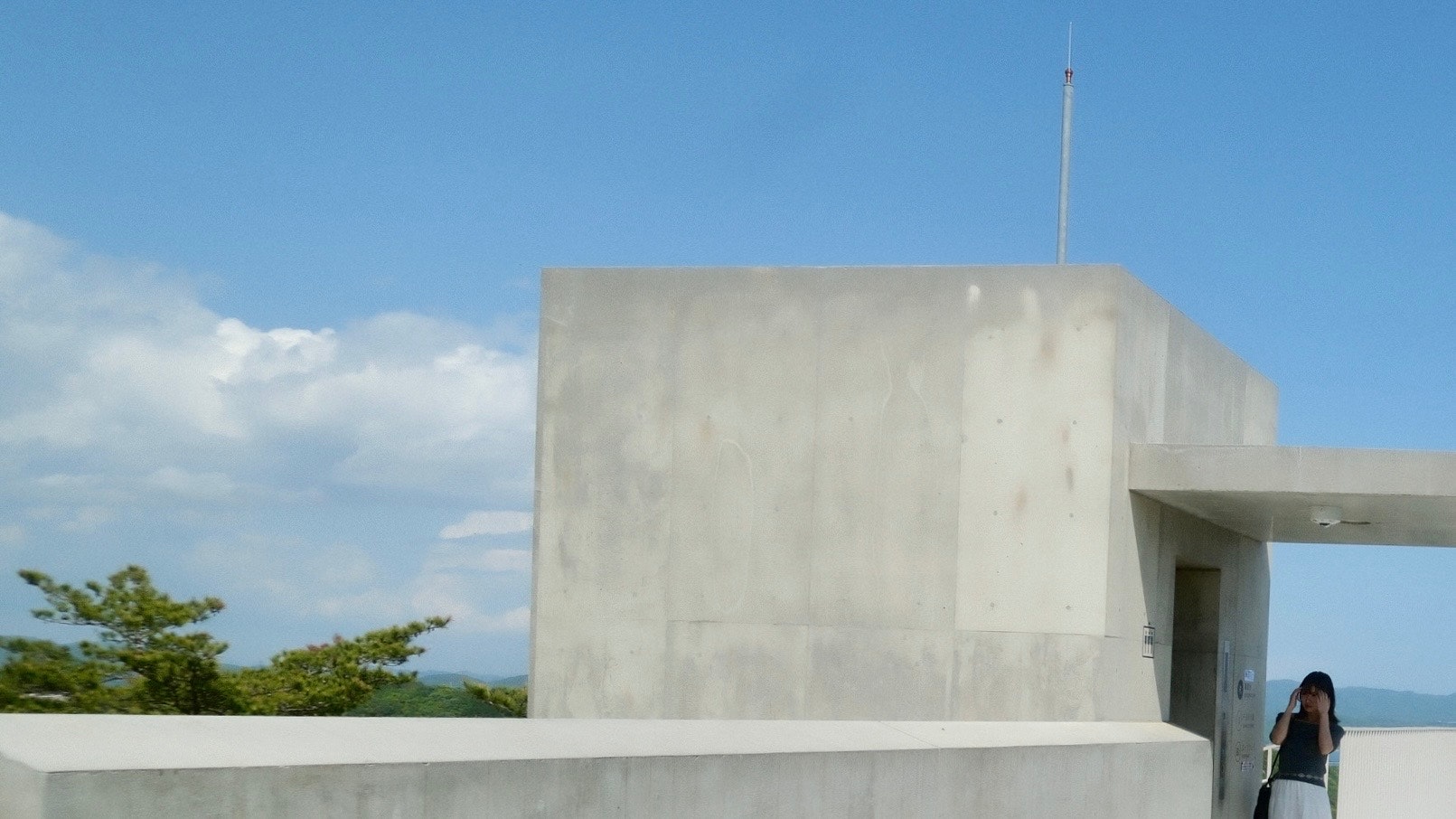 青空の下、屋上のコンクリート建物と影のある空間