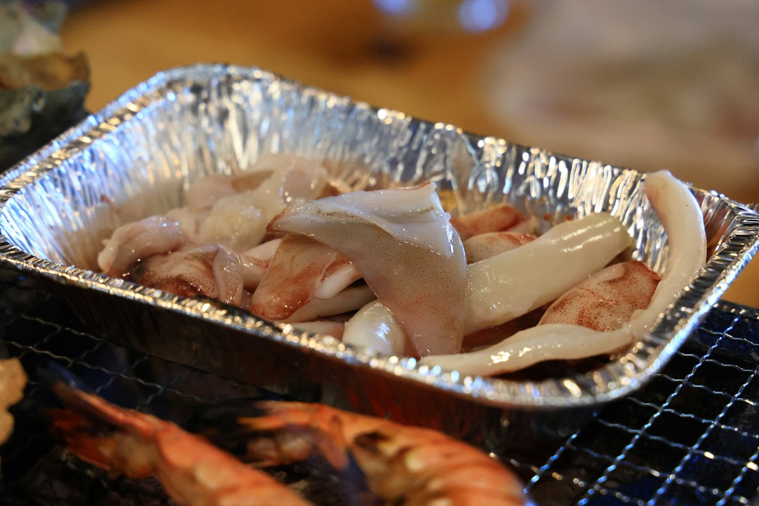 Ein Tablett mit Meeresfrüchten auf einem Grill mit verschiedenen Fischarten und Tintenfisch