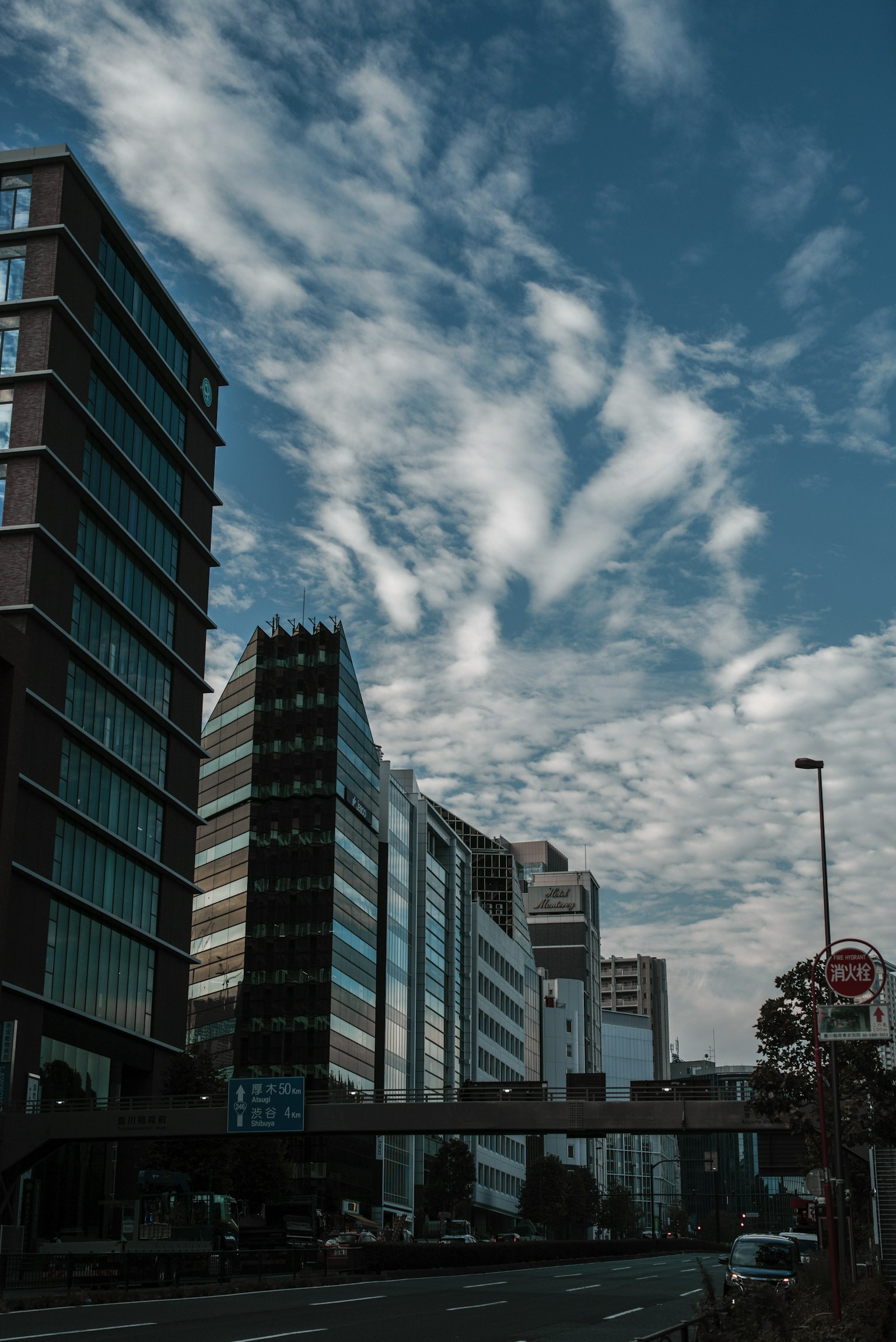 Pemandangan kota dengan gedung tinggi di bawah langit biru dengan awan yang tersebar